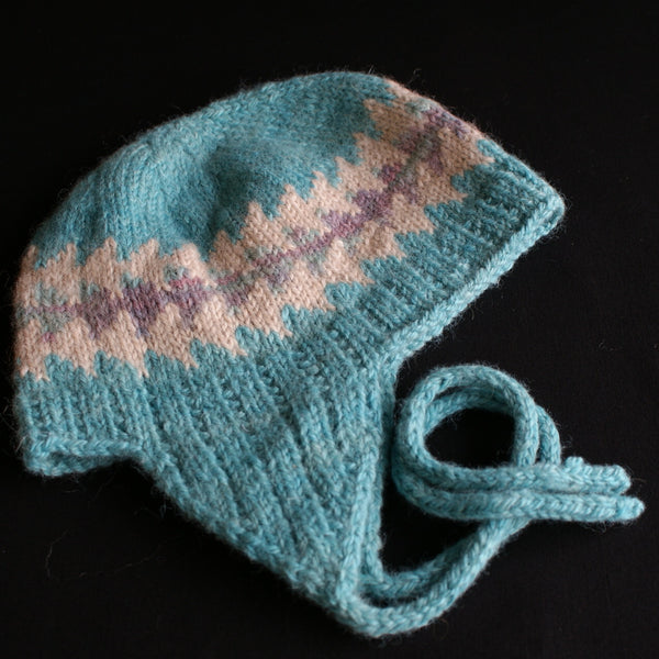 A light turquise hat wth cream and multicoloured bands knit un with earflaps and ties