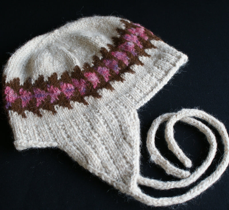a dream coloured hat  with ear flaps and brown and pink decorative stripes knit in