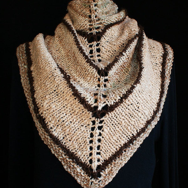 Handknit shawl worn as a bandana on the neck of a black clad mannequin on a black background