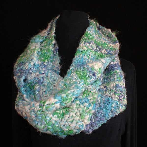 Blue, green, and turquoise infinity scarf on a black mannequin with a black background