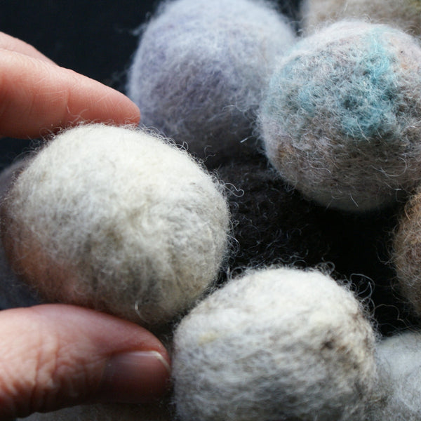 A felted ball held between a thumb and forefinger to illustrate the small size