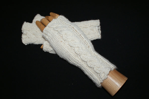 White fingerless mittens knit with a cable up the back . One is on a wooden hand 